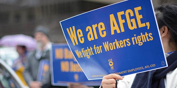 Rally-goer holding sign that says We are AFGE, We fight for Workers rights.