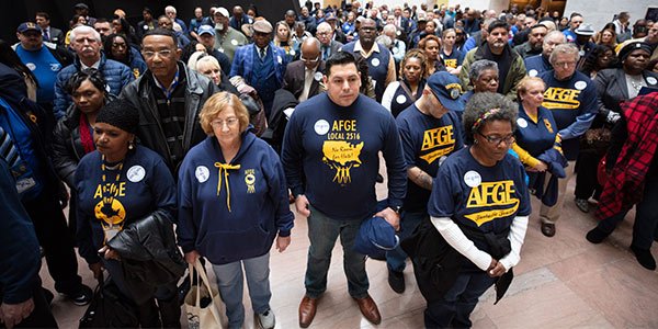 Crowd of AFGE activists stand solemnly at silent protest in the Hart Senate Building. 