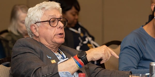 Howard Egerman is seated speaking at a meeting. 