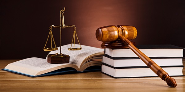 Gavel on top of a stack of books next to legal scales.