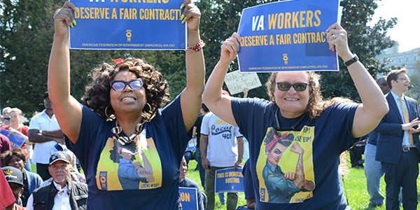 Two women at a rally on Capitol Hill holding signs that say VA Workers Deserve a Fair Contract