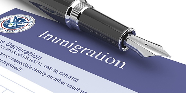 Image of form with the word Immigration at the top. A calligraphy pen is at the top of the form. 