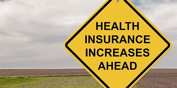 Yellow roadway sign that says Health Insurance Increases Ahead