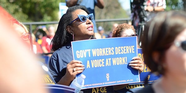 Rally goer holding a sign that reads Gov't Workers Deserve a Voice at Work