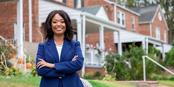 Janeese Lewis George standing in front of a row of houses