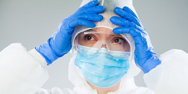 Medical professional wearing PPE with hands on their forehead