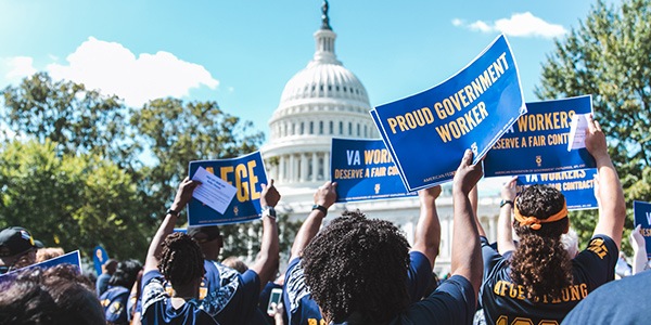 Rally goer outside of US Capitol holding sign that says Proud Government Worker