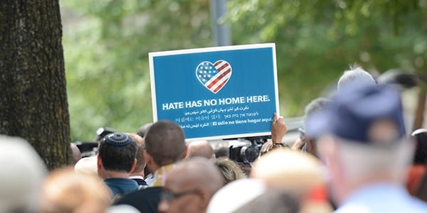 Sea of marchers and someone holding a sign that reads Hate Has No Home Here