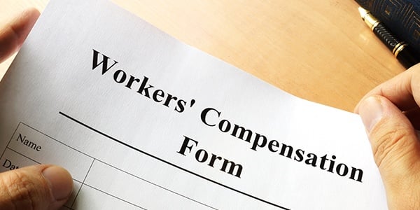 Hands on the sign of a form that reads Workers Compensation Form