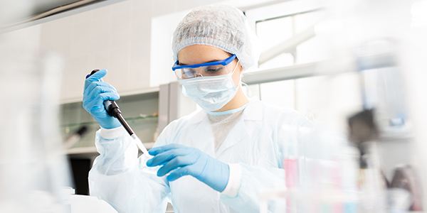 Woman wearing PPE and using a pippet