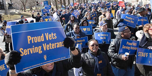 Rally with participant holding sign that reads Proud Vets Serving Veterans