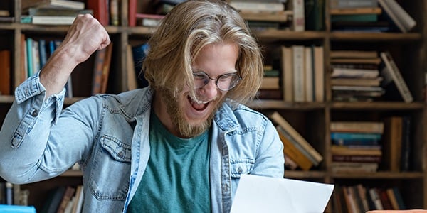 Man raising fist in excitement reading a letter