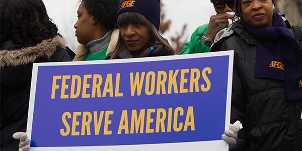 AFGE activist holding sign that reads federal workers serve America