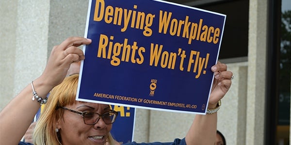 AFGE activist holding sign that reads Denying workplace rights won't fly