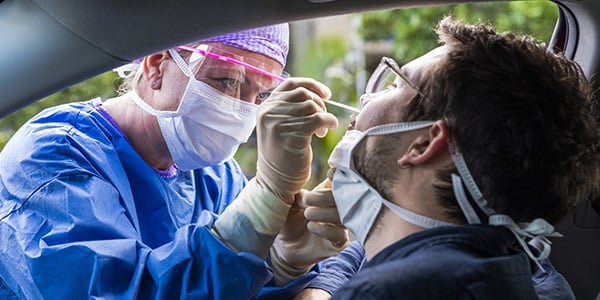 Medical professional administers a COVID test to person sitting in their car