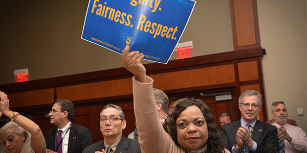 Black woman holding sign that reads Dignity. Fairness. Respect.