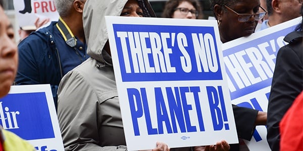 Activist at rally holding sign that reads There's no Planet B