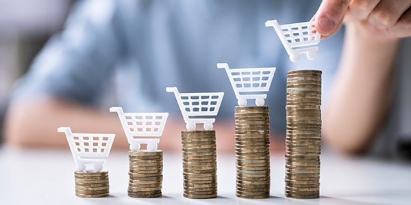 Person stacking small shopping carts over stacks of coins