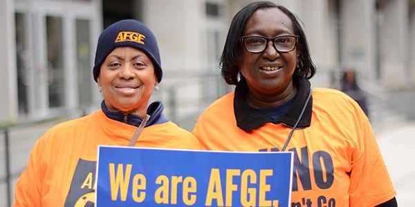 Members holding a sign that says "We are AFGE, we fight for workers right!"