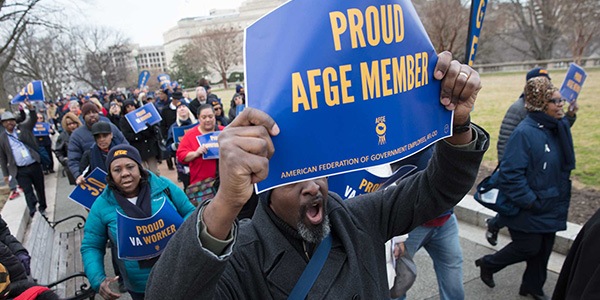 Member holds sign over head that reads Proud AFGE Member