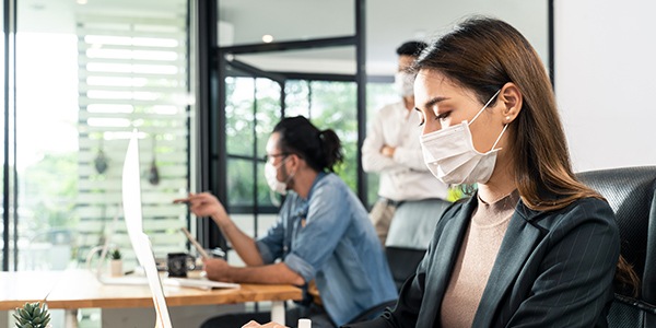 Woman working at desk with mask on