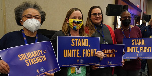 Members holding signs inside LegCon 2022 main room