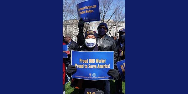 Rall-goer holding sign that reads Proud DoD Worker Proud to Serve America!