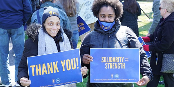 Rally-goers holding signs that read Thank you and Solidarity=Strength