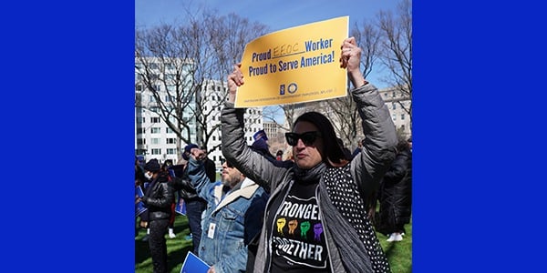 Rally-goer holding sign that reads Proud EEOC worker. Proud to serve America!