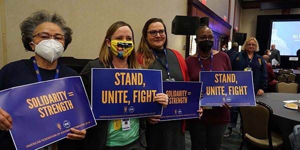 Conference attendees holding signs expressing strength and solidarity.