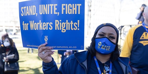 AFGE activist holding rally sign that reads Stand, Unite, Fight for Workers Rights