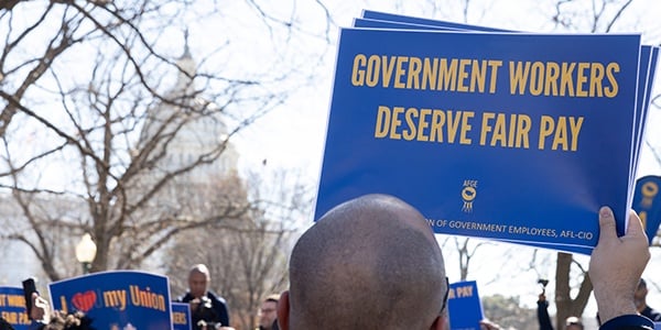 AFGE activist holding rally sign that reads Government Workers Deserve Fair Pay