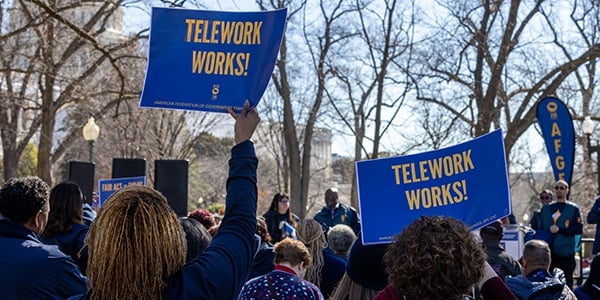 AFGE rally goers with signs that say telework works