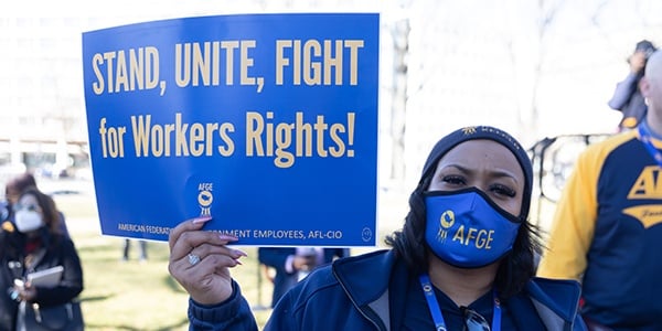 Member with sign that reads Stand Unite Fight for Workers Rights