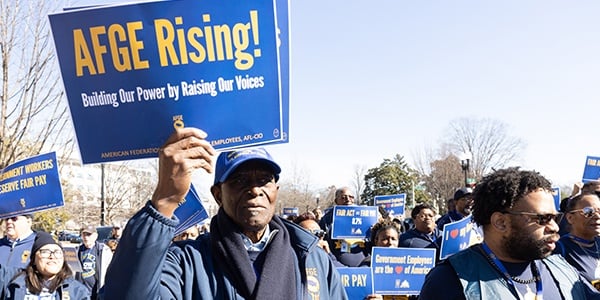 AFGE activist holding rally sign that says AFGE Rising