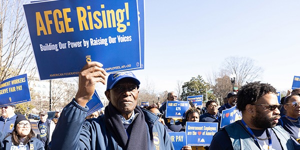 Member holding an AFGE Rising sign at a rally.