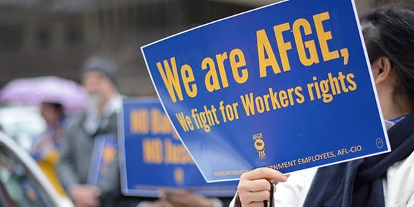 Image of AFGE rally attendee holding sign that says We are AFGE, We Fight for Workers' Rights