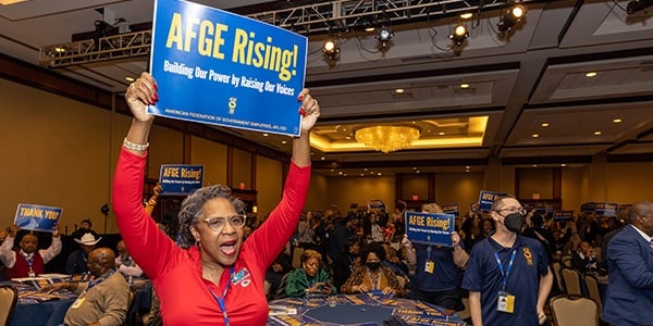 AFGE activists waves sign during conference.