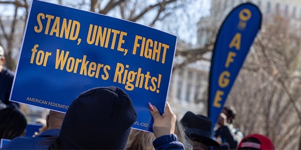 Activist holds sign that reads Stand Unite Fight for Workers' Rights