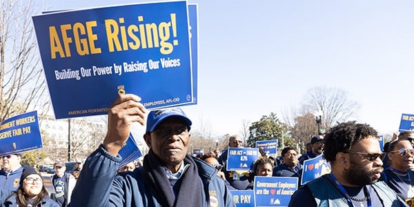 AFGE activist with rally sign that reads AFGE Rising