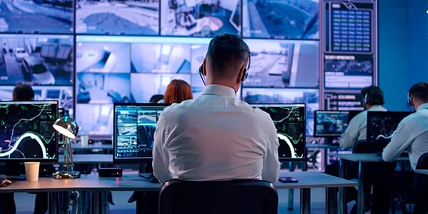 Worker at a computer with multiple monitors in the background. 