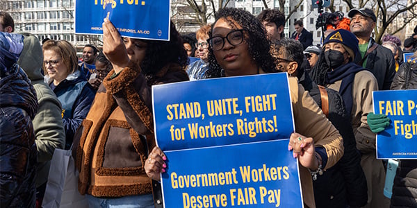 AFGE activist holding two rally signs